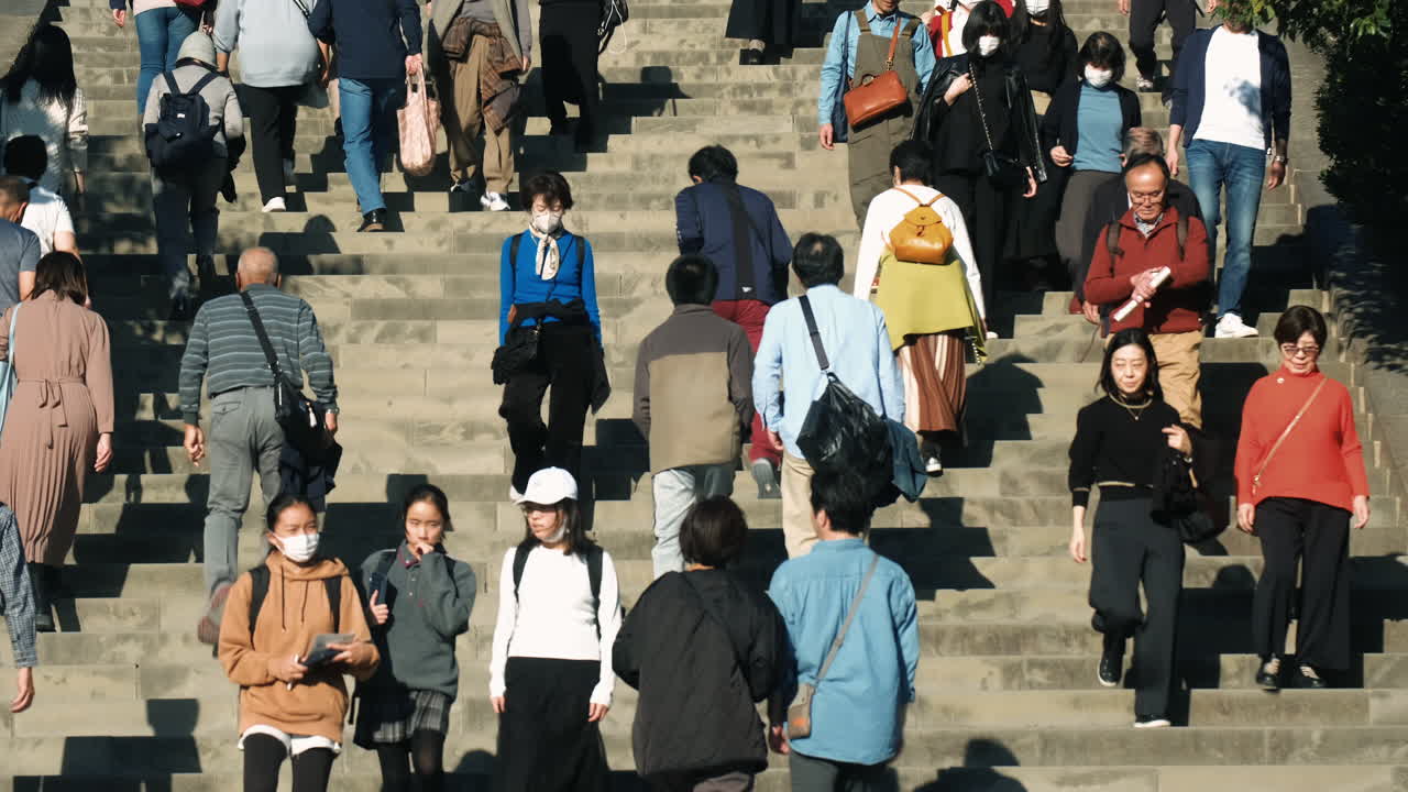 A crowd of people walking up and down a wide set of outdoor stairs