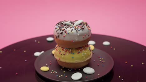 choco crumbs fall on two chocolate american donuts topped with yellow and blue chocolate