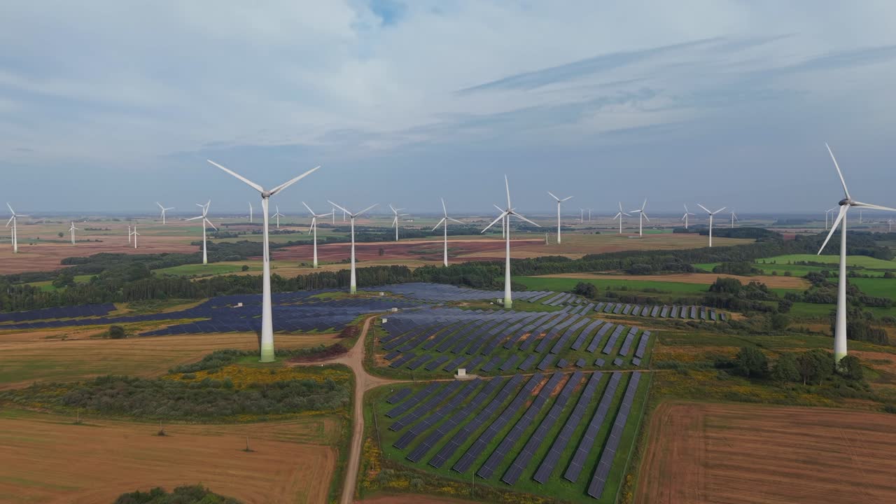 Aerial view of a renewable energy landscape with wind turbines and rows of solar panels generating clean electricity across vast agricultural fields