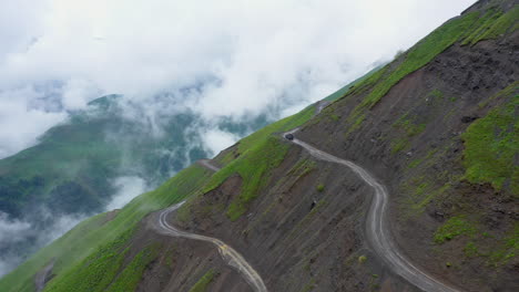 wide cinematic drone shot of vehicle driving on the edge of the abano pass in tusheti georgia, one of the world's most dangerous roads