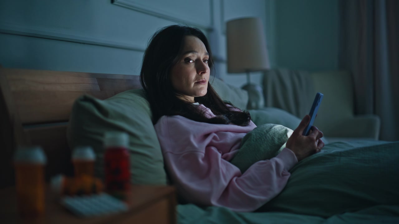 Upset lady watching mobile phone looking medicine bottles at evening closeup