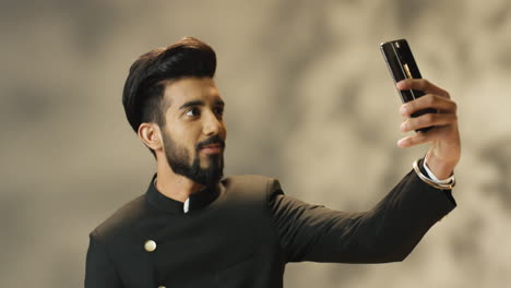 joven indio alegre con ropa tradicional haciendo un selfie con smartphone