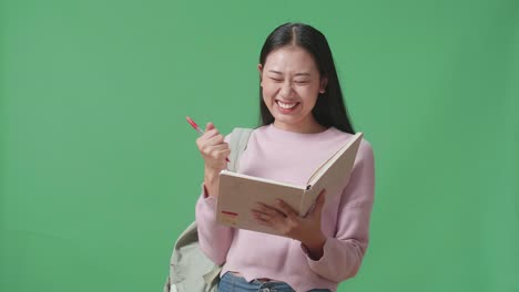 asian woman student note on book and celebrating in green screen studio