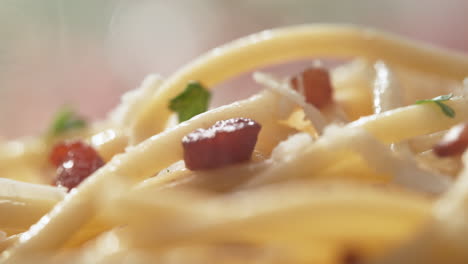 macro shot of spaghetti carbonara sprinkled with grated pecorino cheese and garnished with fresh chopped parsley - camera moves to the left