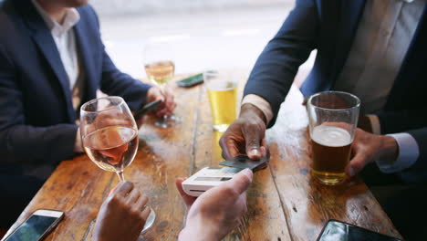 Close-Up-Of-Businessman-Paying-For-Round-Of-Drinks-In-Bar-After-Work-Using-Contactless-Card