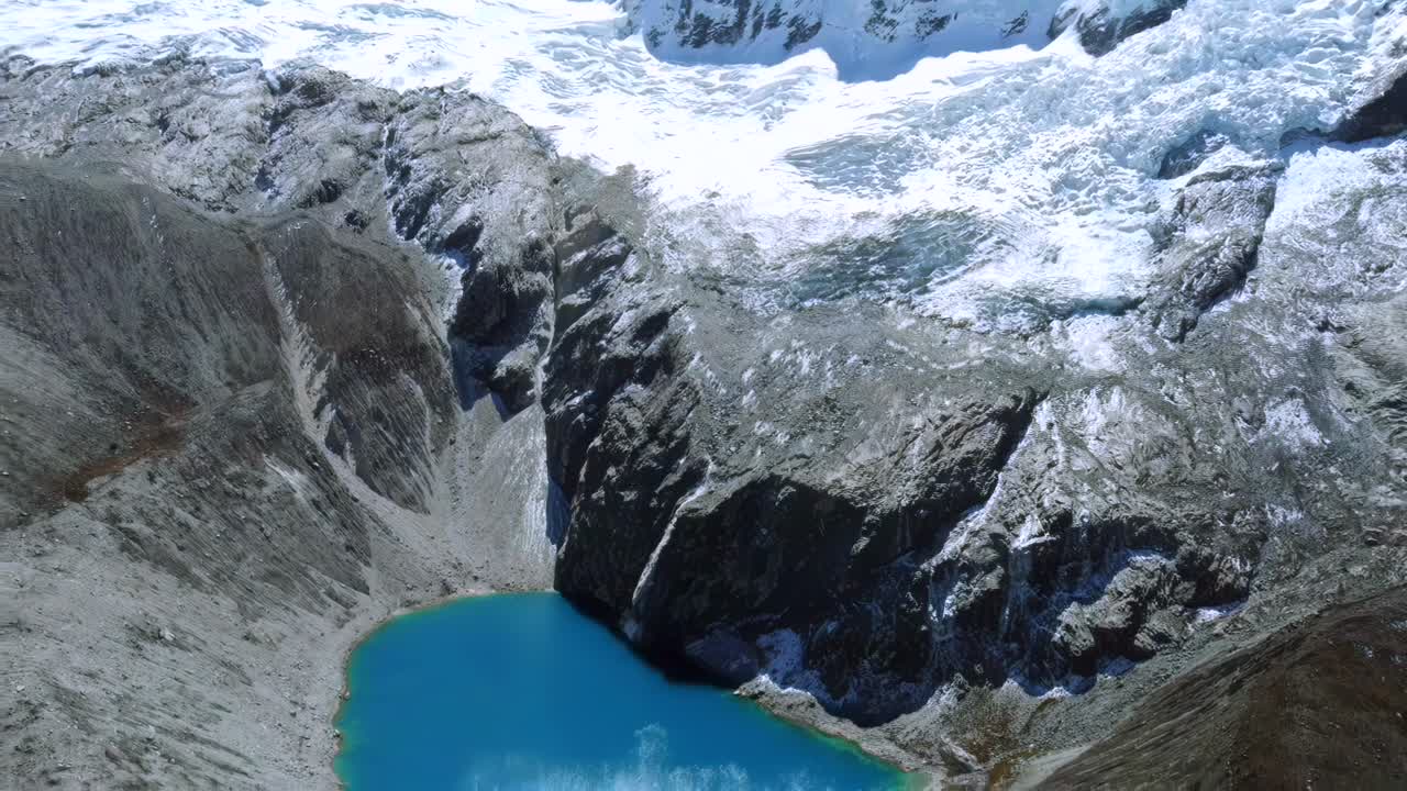 Stunning aerial tilt down above Laguna 69 in Huaraz, Peru, turquoise waters surrounded by towering Andean peaks