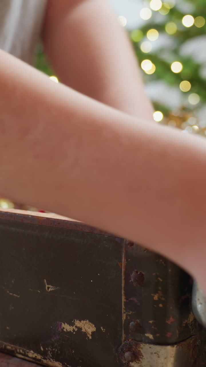 빈티지 장식품 여행 가방을 열어보는 백인 남자아이. 조심스러운 손으로 낡은 금속 케이스를 열어 유리 장식, 얇은 금속 조각, 조명을 꺼내고, 향수를 불러일으키는 휴일의 추억, 소박한 녹청, 클로즈업 디테일, 따뜻한 보케를 표현했어요.