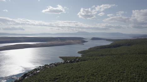video con drone plano frontal avanzando sobre la costa de jadranovo y la isla de san marcos en croacia, al fondo se puede ver el puente krcki, un muelle con barcos en la orilla