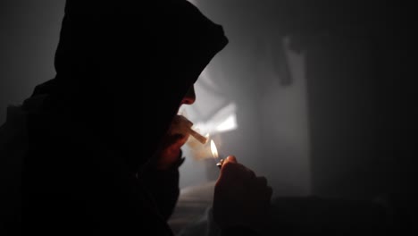 a young man lights up a marijuana joint and smokes it