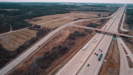 aerial-above-highway,-semi-trucks,-cars-driving