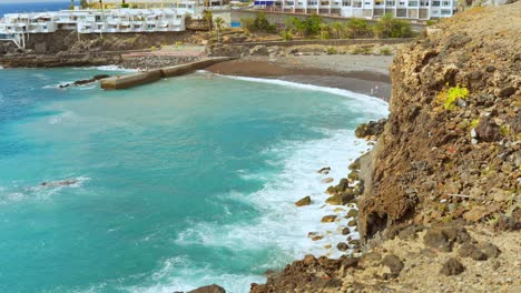 View-at-tourist-resort-on-coast,-turquoise-wavy-ocean-and-cliffs