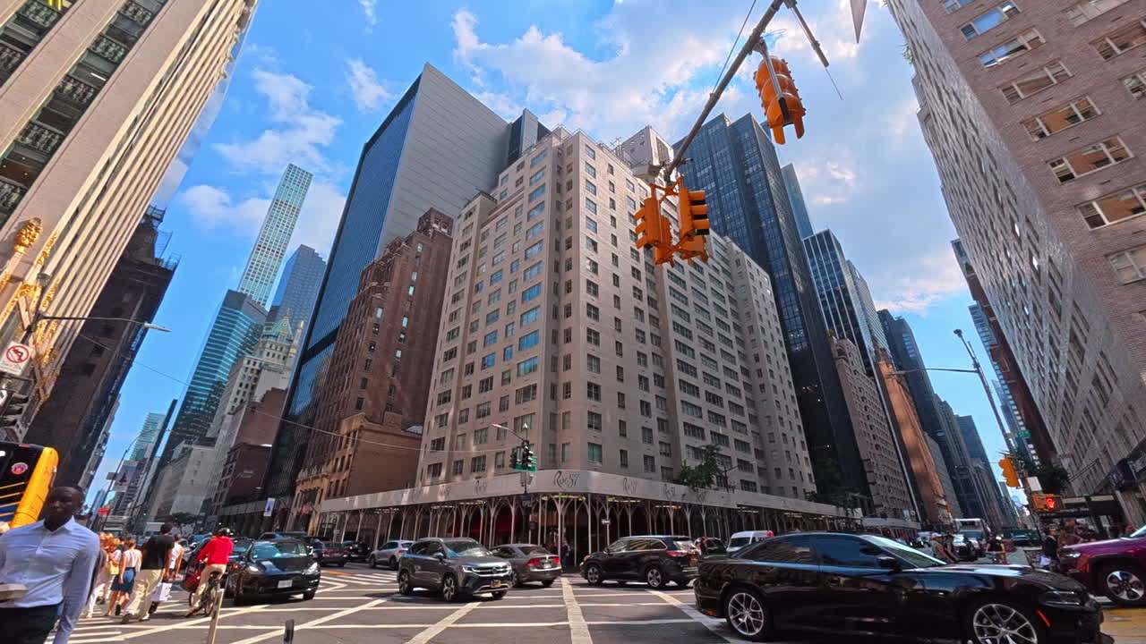 New York, USA, 1 August 2025: Intersection in Manhattan surrounded by skyscrapers. Urban view of Manhattan intersection with pedestrians, cars, and tall buildings
