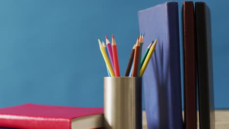 Video-of-crayons-in-container-and-books-on-blue-background