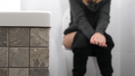 woman sitting on toilet in bathroom