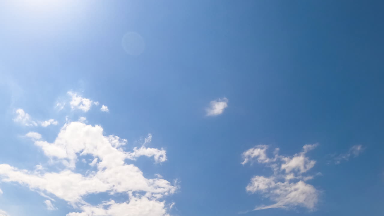 Sun lighting the cirrus clouds in the azure skies. Big grey cloud appears and covers the sky. Low angle view. Timelapse.