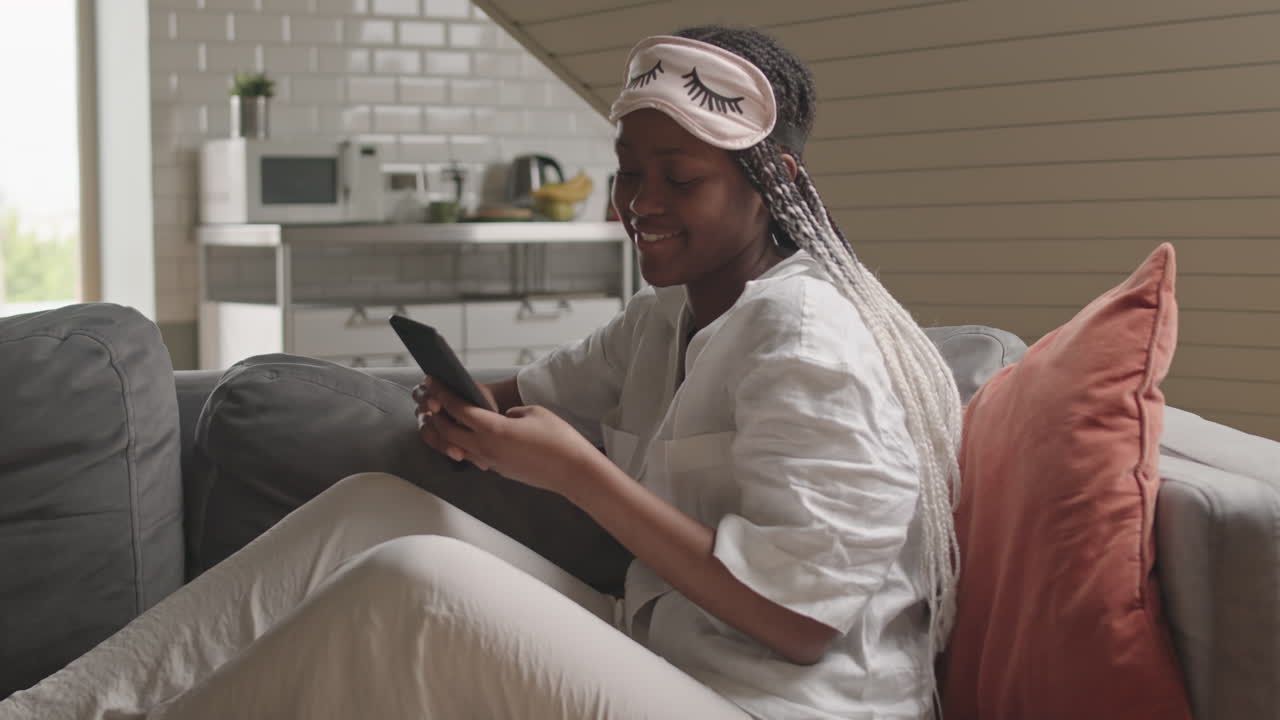African American Woman Scrolling on Smartphone at Home