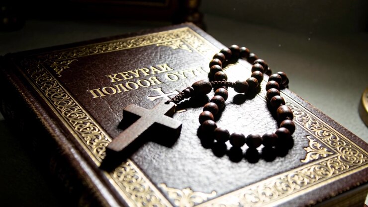 Sweeping warm light drawing camera pan, leather book showing wooden rosary and cross revealing lamp