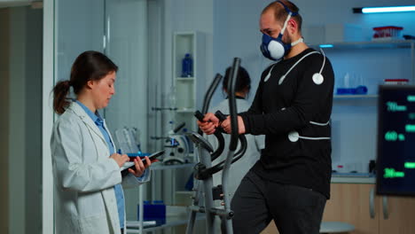 médico preguntando al paciente sobre su salud mientras el deportista corre en cross trainer