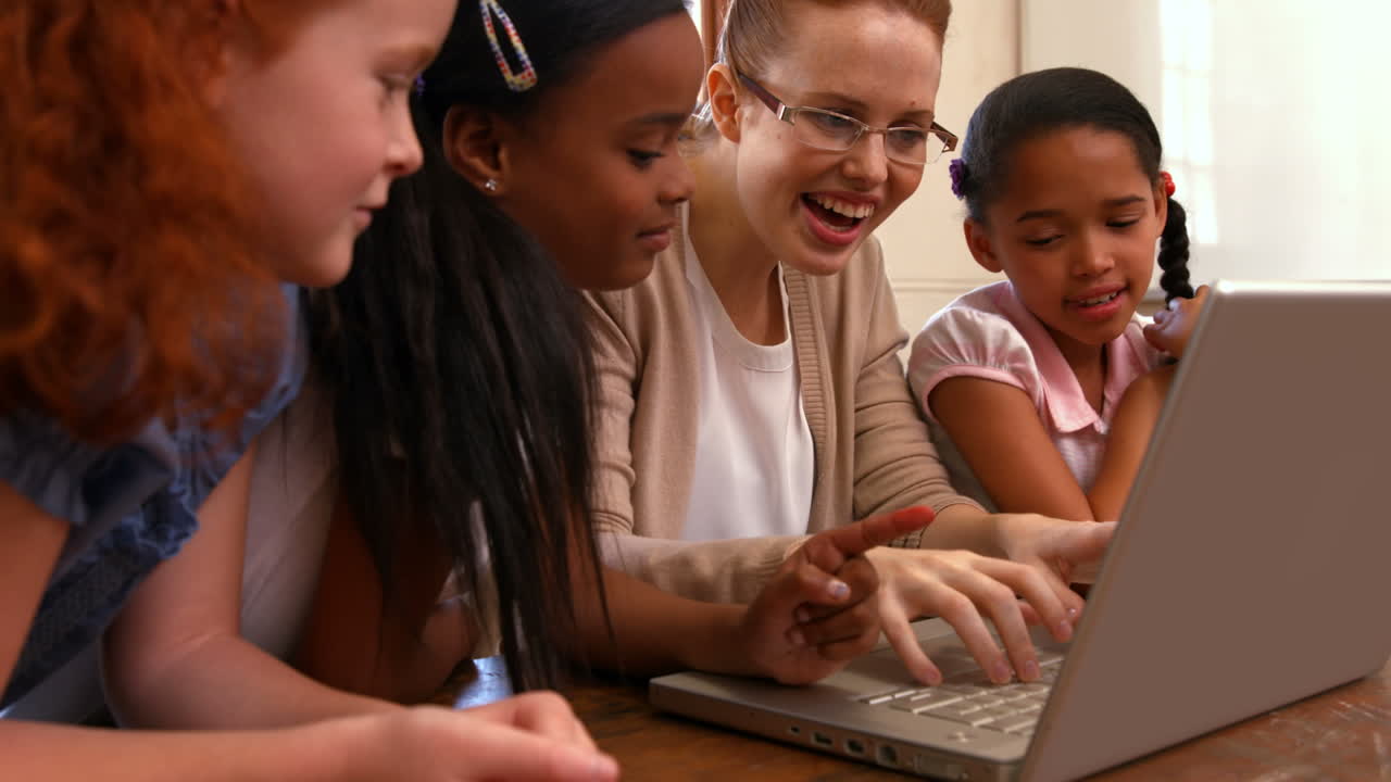 Teacher looking at laptop with pupils