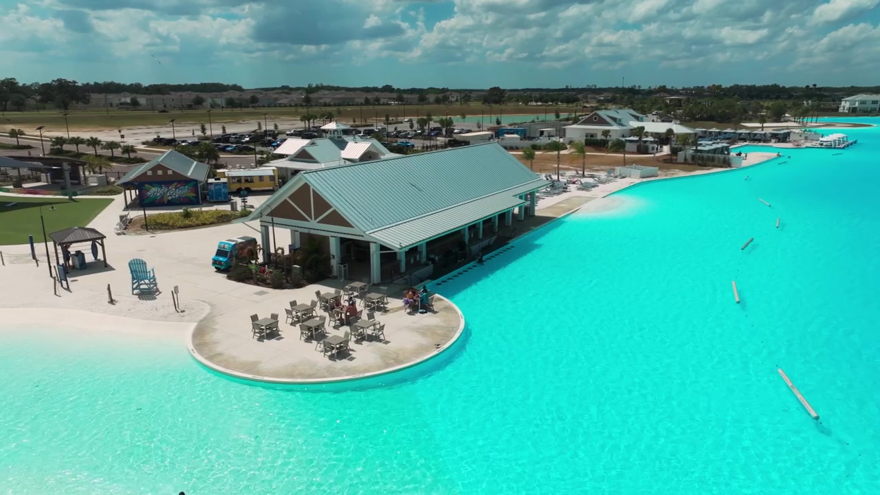 Drohnenperspektive des Strandrestaurants an der Lagune in San Antonio, Florida, wo Gäste die Sonne am funkelnden türkisfarbenen Wasser genießen