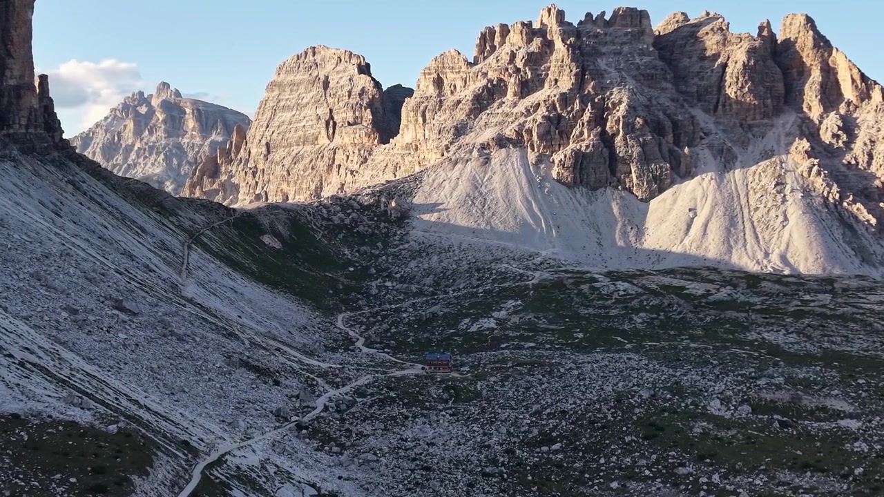 Dolomitler, İtalya'daki Rifugio Lavaredo ve kayalık yürüyüş parkurlarının üzerinde yükselen Tre Cime di Lavaredo'nun drone görüntüsü