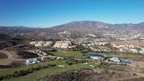 Carro-Aéreo-Hacia-Casas-De-Lujo-Que-Bordean-El-Campo-De-Golf-En-Un-Día-Soleado-En-España