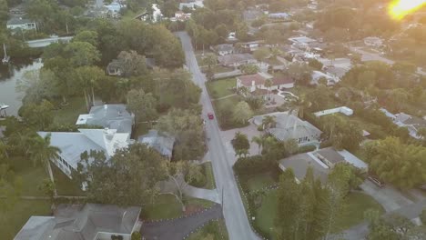 Vista-Aérea-De-Un-Auto-Deportivo-Rojo-Conduciendo-Por-La-Calle-Del-Sur-De-Florida-Al-Atardecer