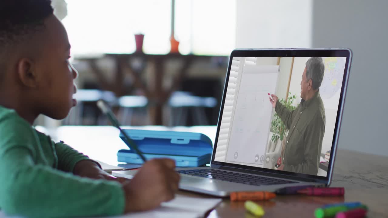 African american boy having a video call on laptop while doing homework at home
