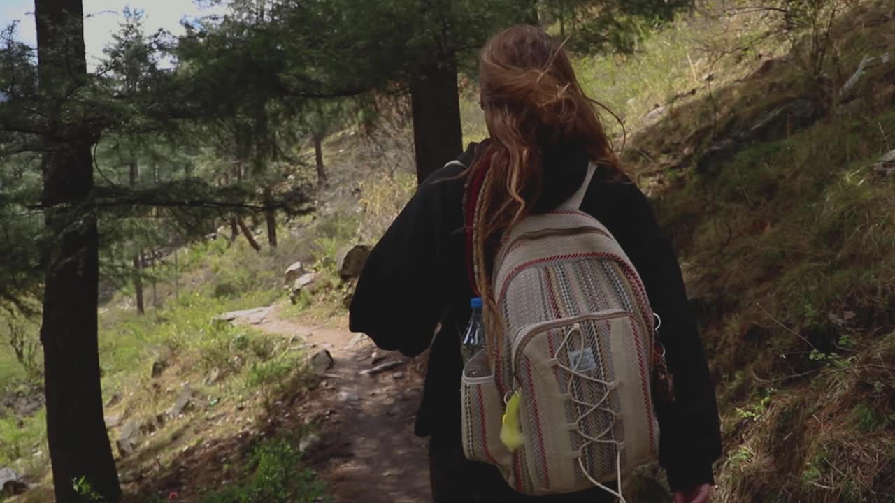 woman walking in a forest trail with a backpack  - Parvati Valley - Himachal Pradesh - Himalayas, India