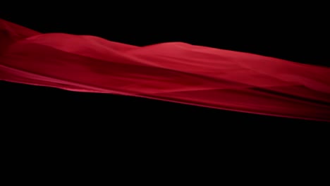 red silky fabric floating beautifully in the air with black background - studio shot