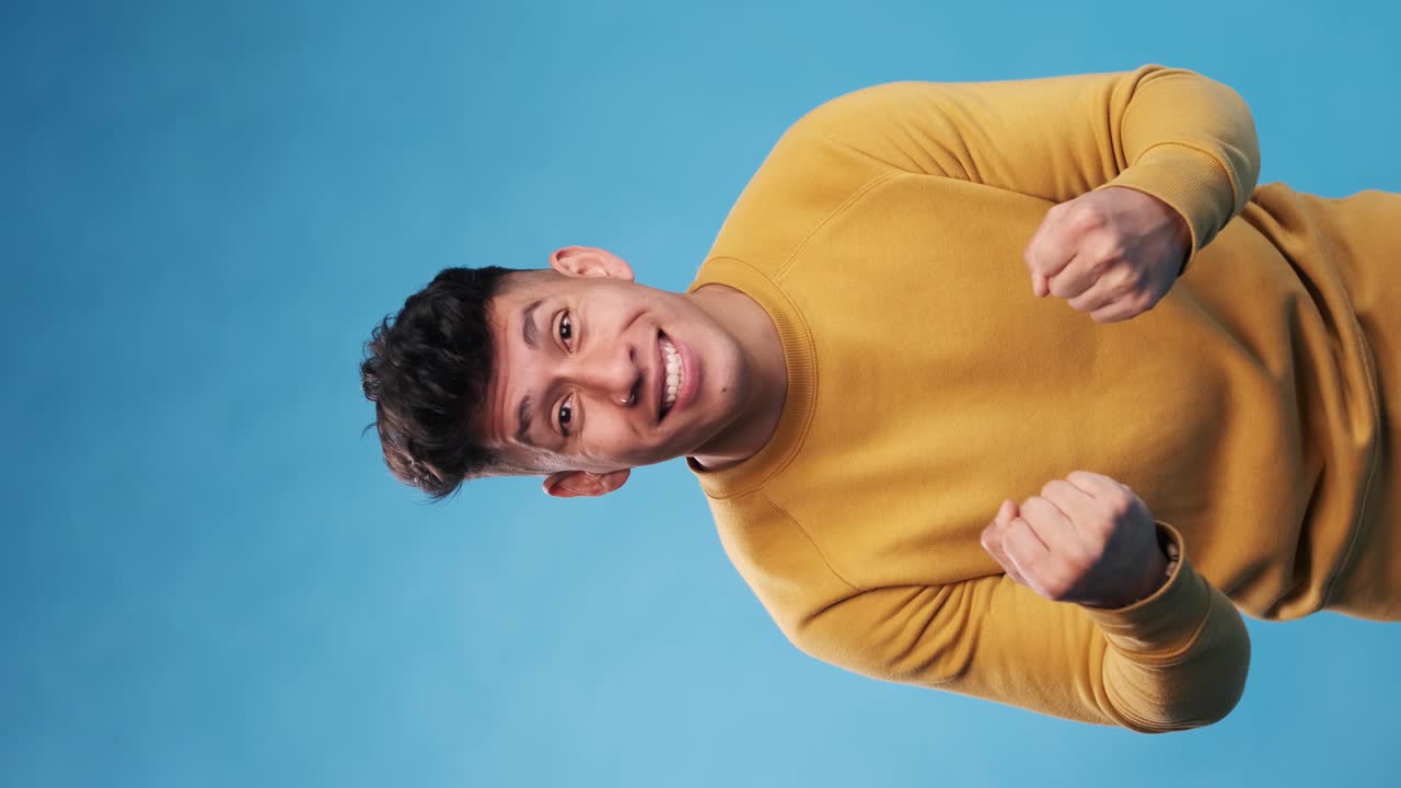 Excited man looking at camera while celebrating good news against an isolated background.
