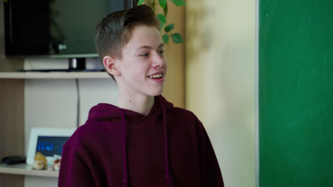 Portrait of a teenage boy at school. Smart school boy standing near the blackboard and answering questions. Education at school.