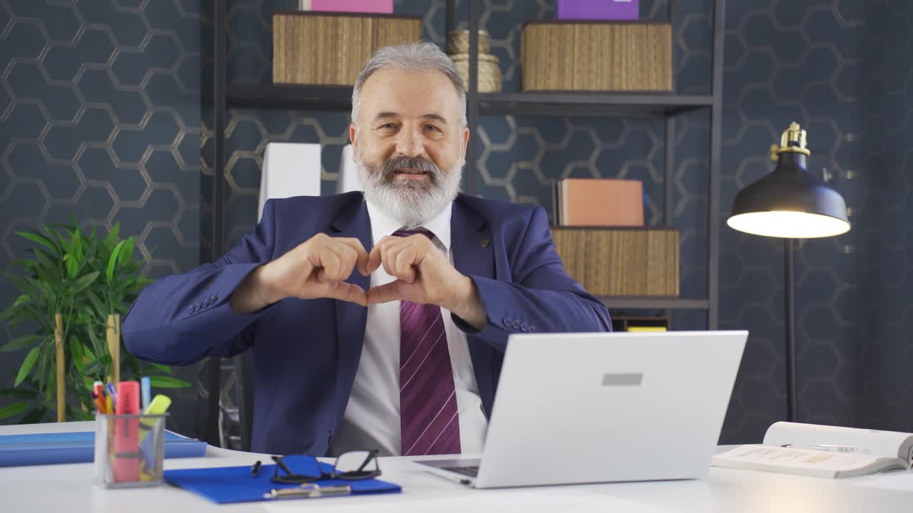 un hombre de negocios amoroso haciendo el símbolo del corazón ante la cámara.