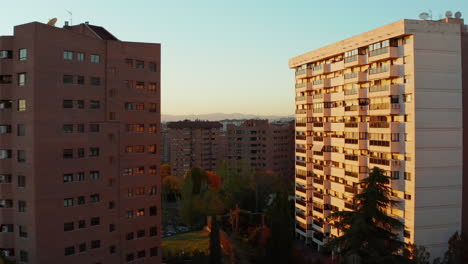 Forwards-fly-between-and-over-residential-houses-in-housing-estate-at-golden-hour.-Autumn-colourful-foliage-on-trees.