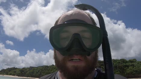 caucasian, bearded man take a selfie of himself putting on a snorkelling mask and diving underwater