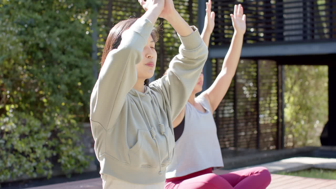 집중된 아시아 여성 친구들이 이 많은 테라스에서 요가 명상을 연습하고, 느린 동작