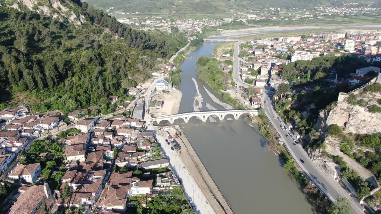 vista de avión no tripulado en albania volando en la ciudad de berat mostrando casas medievales con techos de ladrillo al lado con un río y un puente blanco