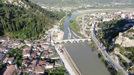 drone view in albania flying in berat town showing medieval houses with brick roofs next with a river and white bridge