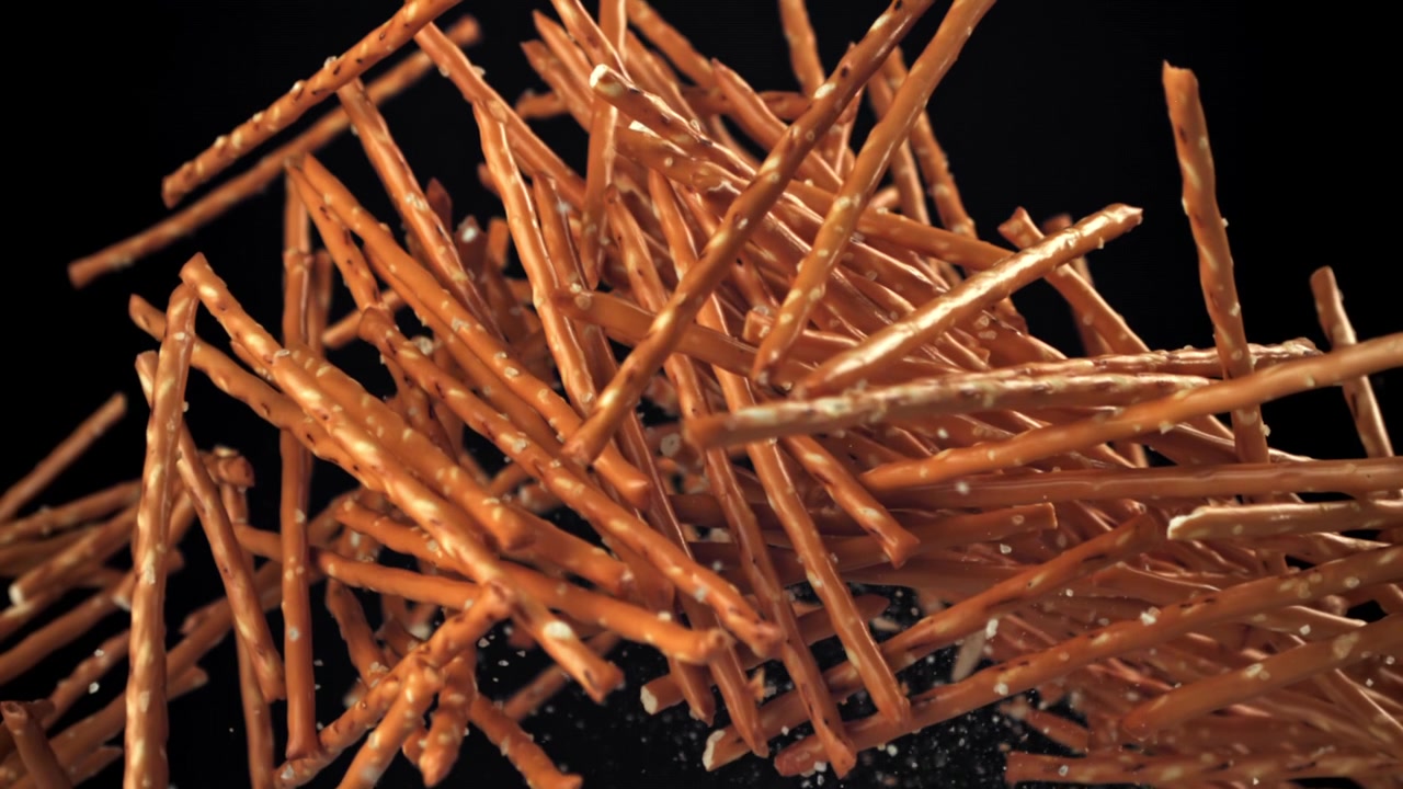 Bastoncini di pretzel salati che cadono e rimbalzano al rallentatore.