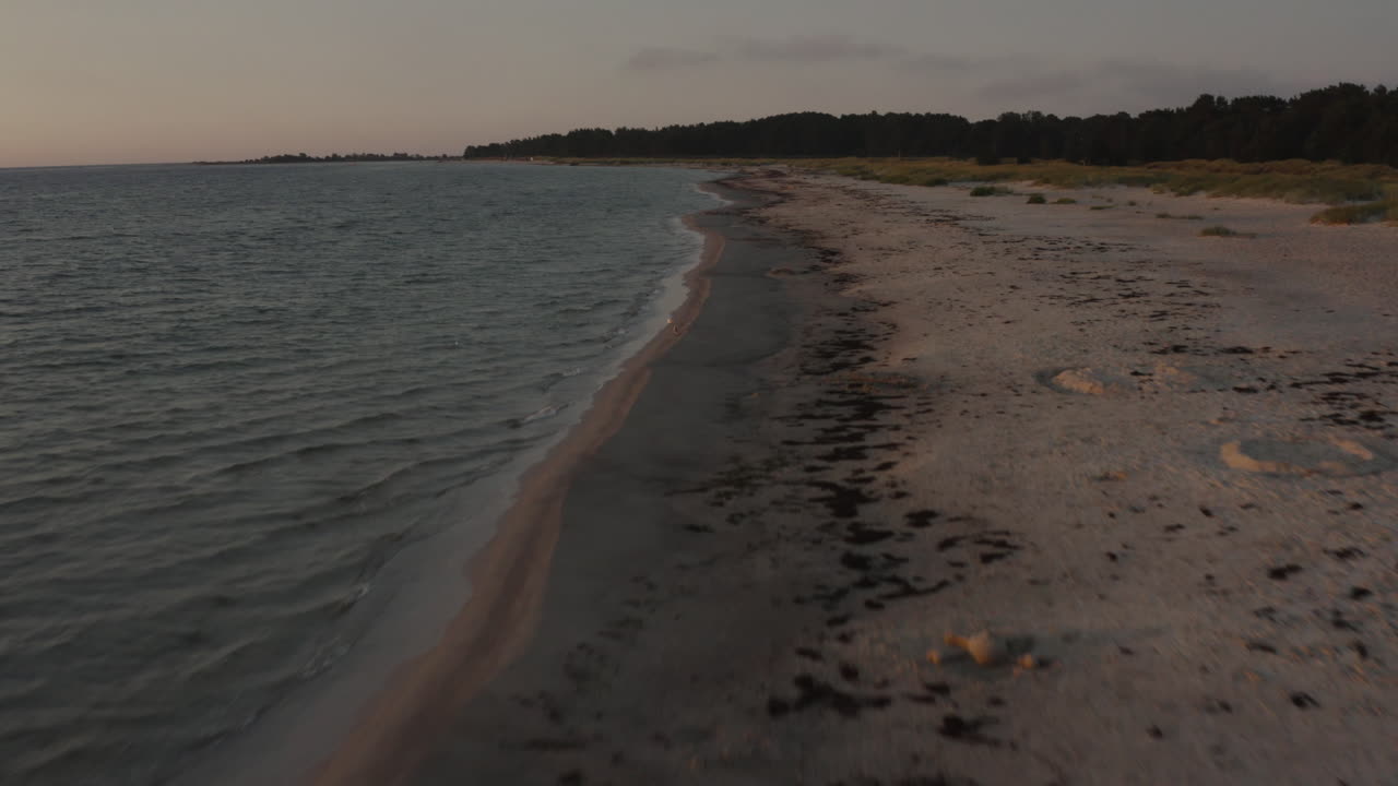 беспилотник 4k пролетает рядом с песчаным пляжем и океанской водой во время солнечного заката