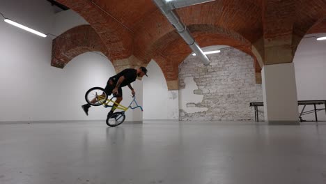 bmx rider doing tricks and then falling inside of a warehouse