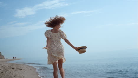 happy girl jumping sandy beach summer day. curly woman running on ocean waves.