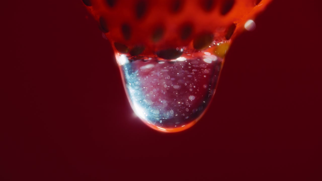 Macro close up of a water drop falling from a strawberry