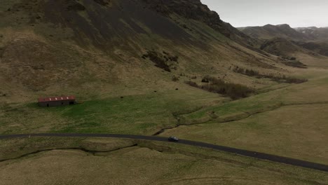 aerial shot of intersecting dirt roads and a winding river in the expansive, rugged valley of brókarjökull, iceland, with mountains in the distance