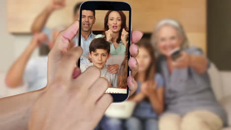 mano mostrando a la gente viendo clips de fútbol en el teléfono inteligente