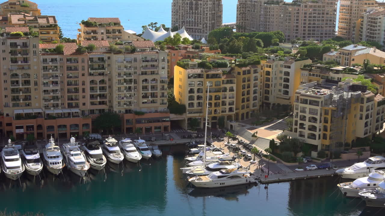 Aerial view of Fontvieille Harbour in Monaco, showcasing its pastel-colored buildings, luxury yachts, and the Mediterranean Sea