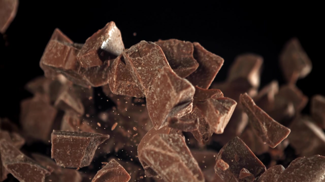 Pezzi di cioccolato che cadono al rallentatore su sfondo nero