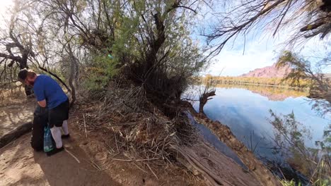 Man pulls out inflatable paddle board underneath Mesquite trees in Mesa Arizona.