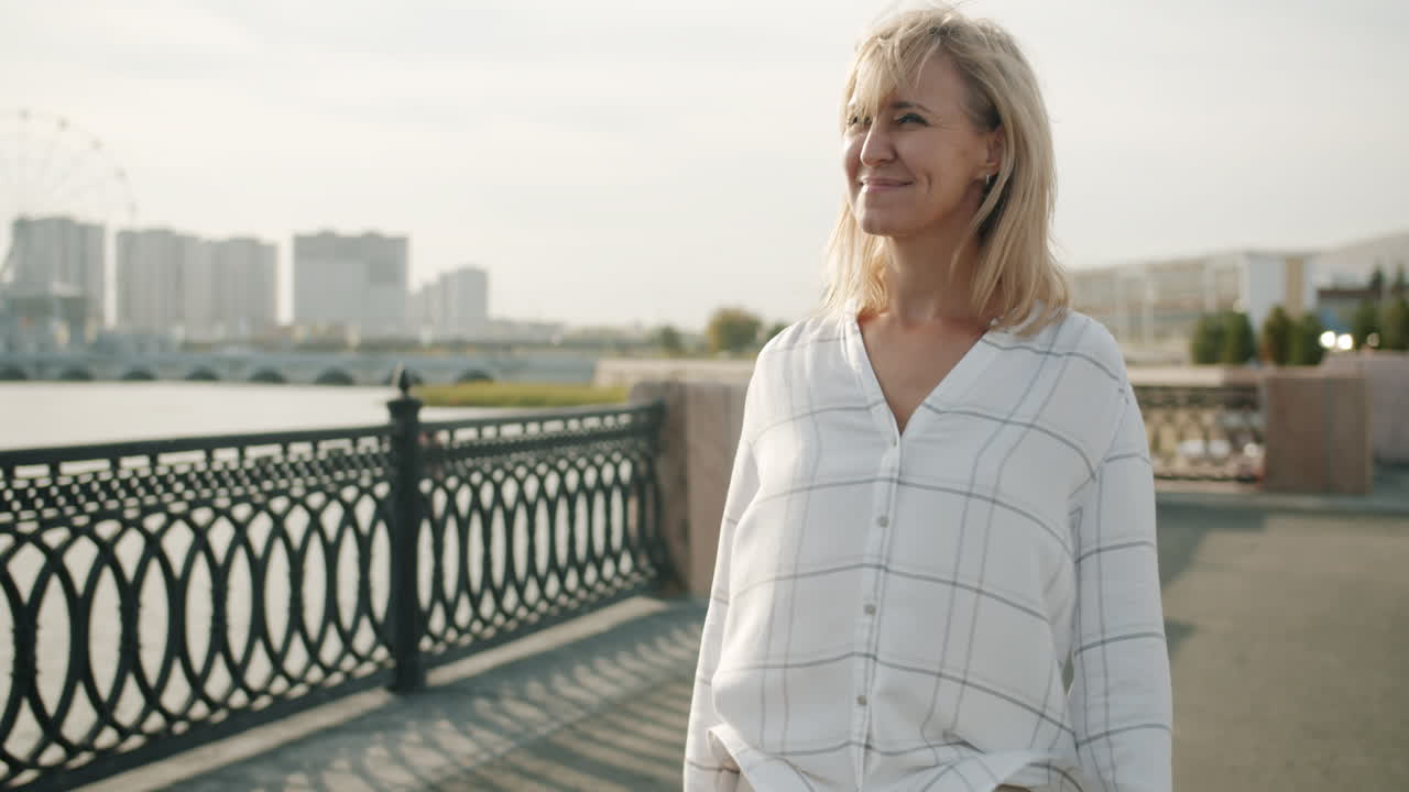 Woman Walking Along the River in City