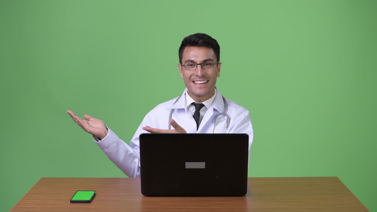 joven hombre hispano guapo médico contra fondo verde